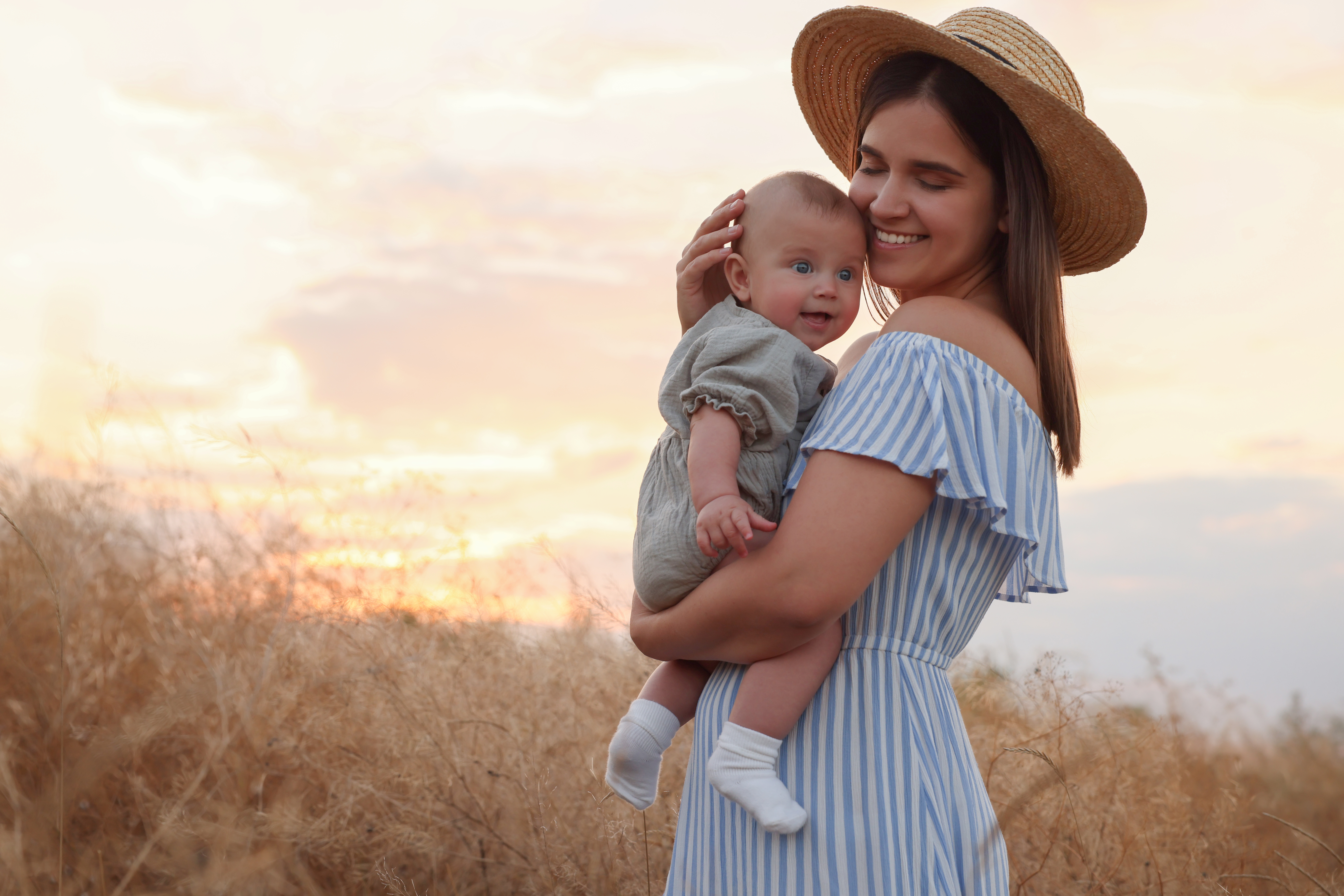 Happy Mother With Adorable Baby In Field At Sunset, Space For Te A woman wondering "Is Adoption Right for Me?"