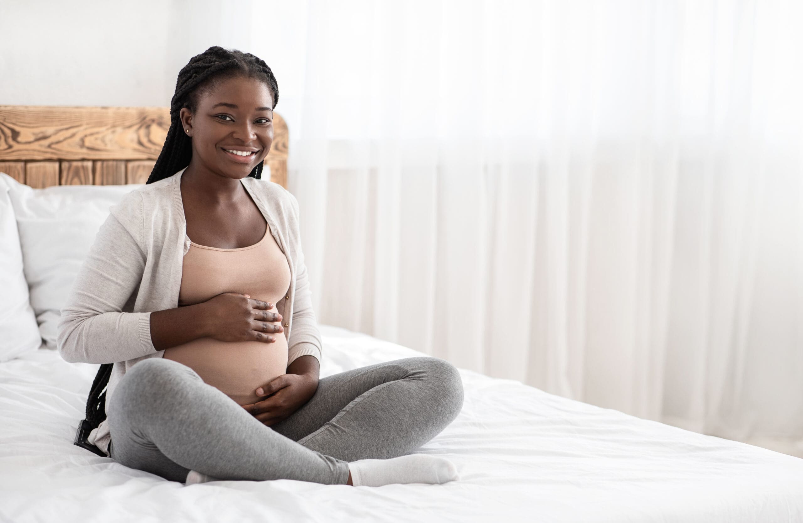 Pregnancy Time. Happy Black Pregnant Woman Sitting On Bed Touchi A woman wondering "How could I choose adoption?"